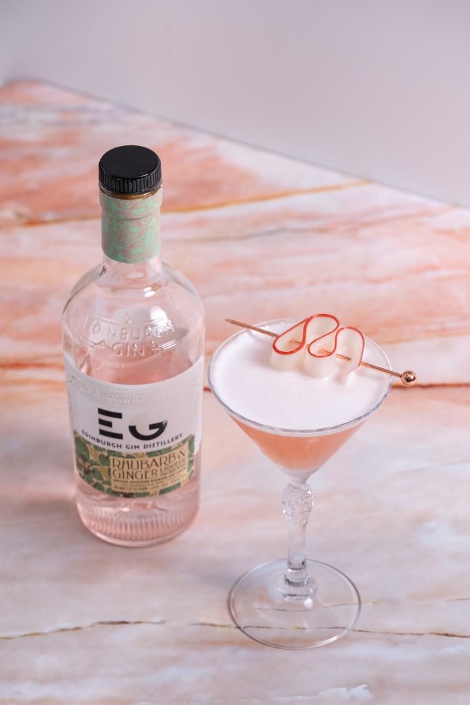 High angle view, vertical image, rhubarb ginger gin cocktail and a bottle of edinburgh distillery rhubarb ginger gin liqueur.